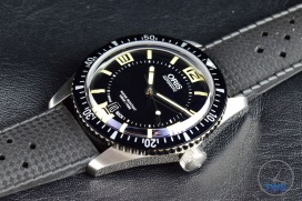 Oris Divers Sixty-Five closeup sitting on black leather with its crown in view [01 733 7707 4064-07 4 20 18]