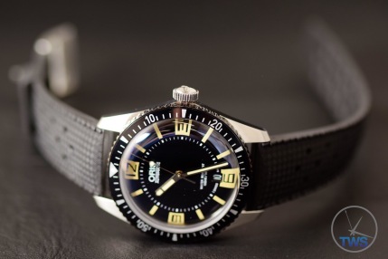 Oris Divers Sixty-Five laying on its side on a black leather surface [01 733 7707 4064-07 4 20 18]