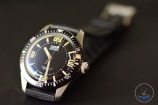 Oris Divers Sixty-Five Laying back on its strap at an angle on black leather with the clasp going out of focus in the background [01 733 7707 4064-07 4 20 18]