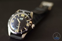 Oris Divers Sixty-Five Laying back on its strap at an angle on black leather with the clasp going out of focus in the background [01 733 7707 4064-07 4 20 18]